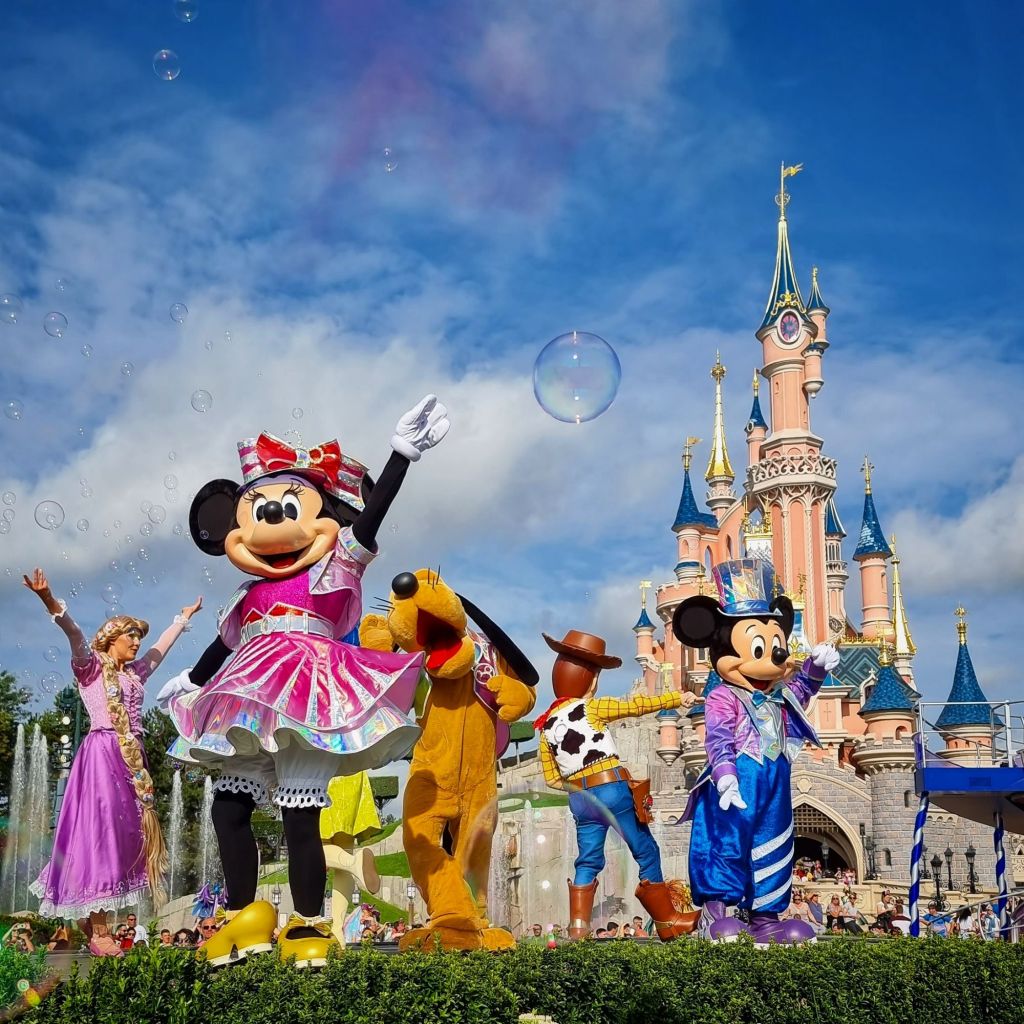 Rapunzel, Minnie, Pluto, Woody, and Mickey in front of the castle during "Dream... and Shine Brighter" at Disneyland Paris